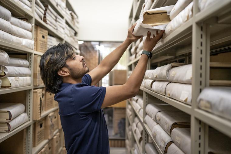 Washington College student Felipe Tassara pulls record books from the shelves of the Maryland State Archives